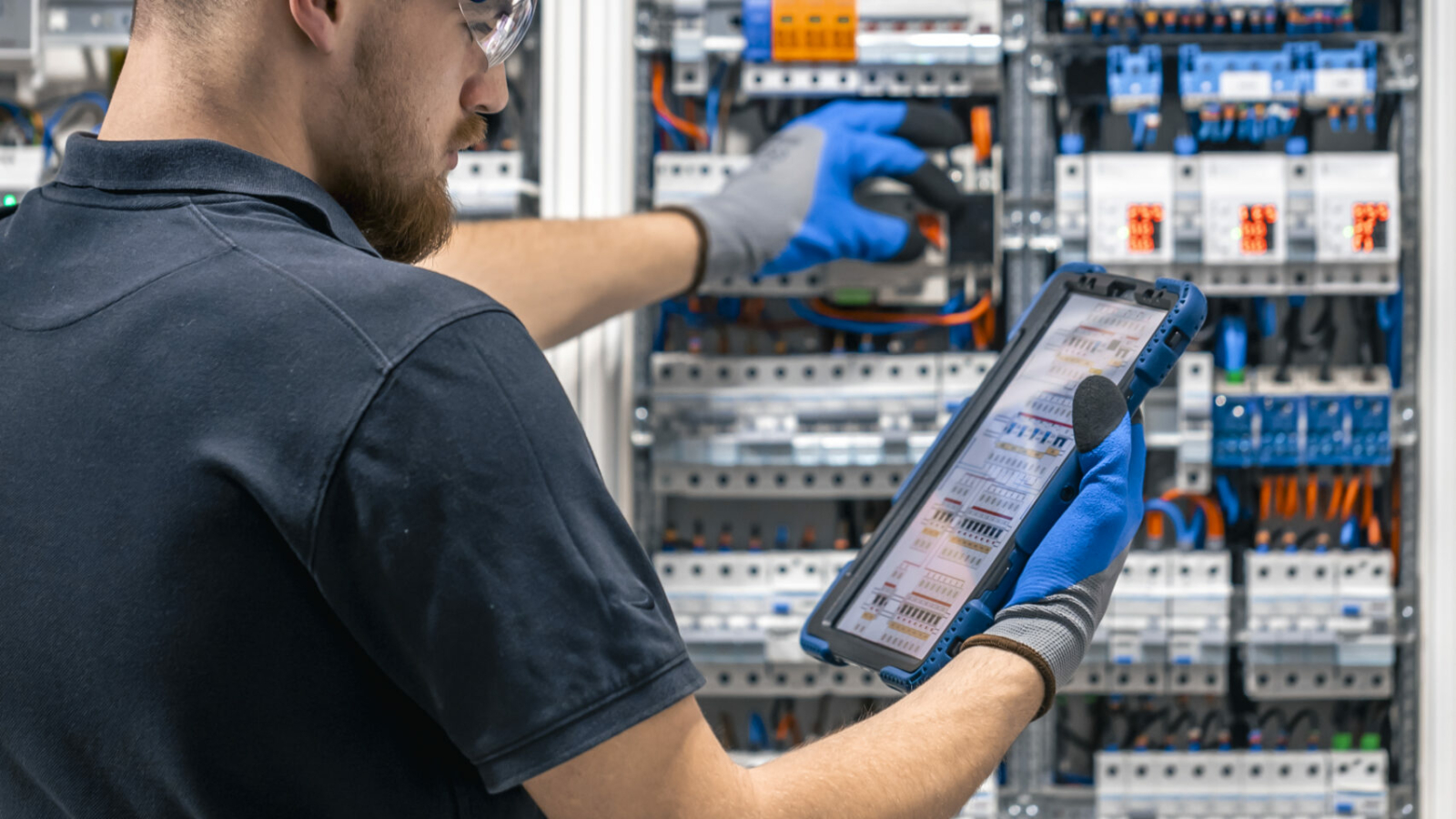 Électricien contrôlant un tableau électrique avec une tablette