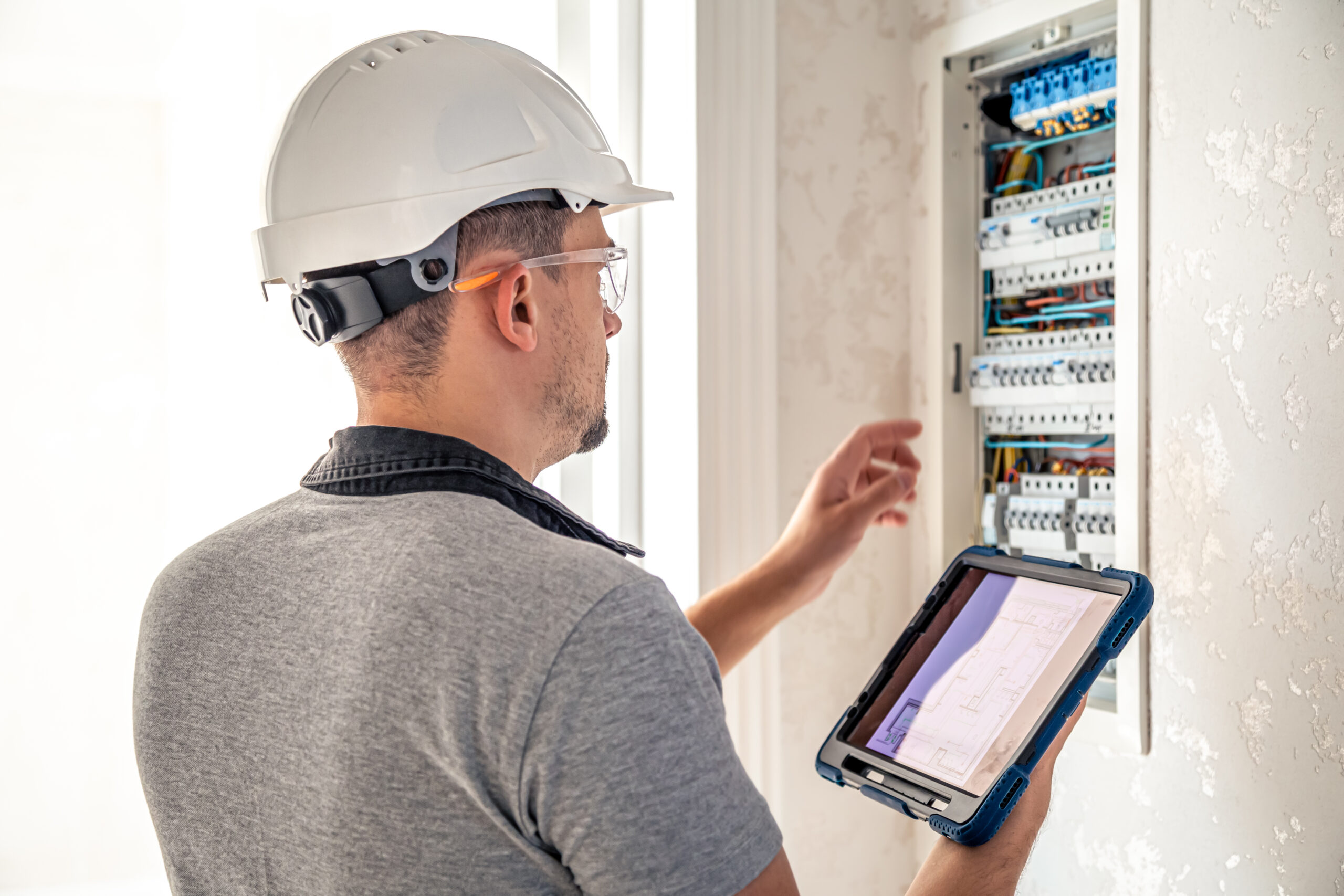 Man, an electrical technician working in a switchboard with fuses. Installation and connection of electrical equipment.